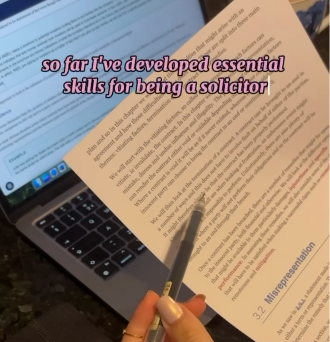 Study scene showing a hand holding a pen over legal documents and papers, with a laptop computer open in the background displaying text on screen. Pink text overlay reads 'so far I've developed essential skills for being a solicitor'. The image captures the practical learning experience of a SQE apprenticeship, showing the combination of digital and paper-based legal work that apprentices engage with while developing their professional skills and studying for qualification.